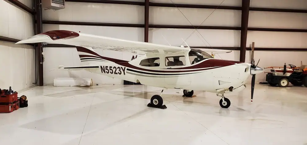 White single-engine airplane detailed inside a hangar