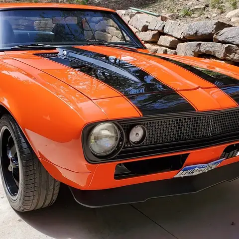 Orange first-generation Chevy Camaro with black stripes after detailing