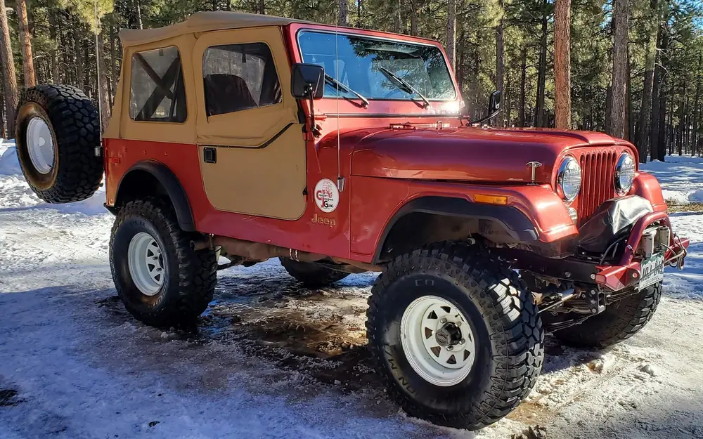 Classic red Jeep CJ-7 on snowy ground after detailing