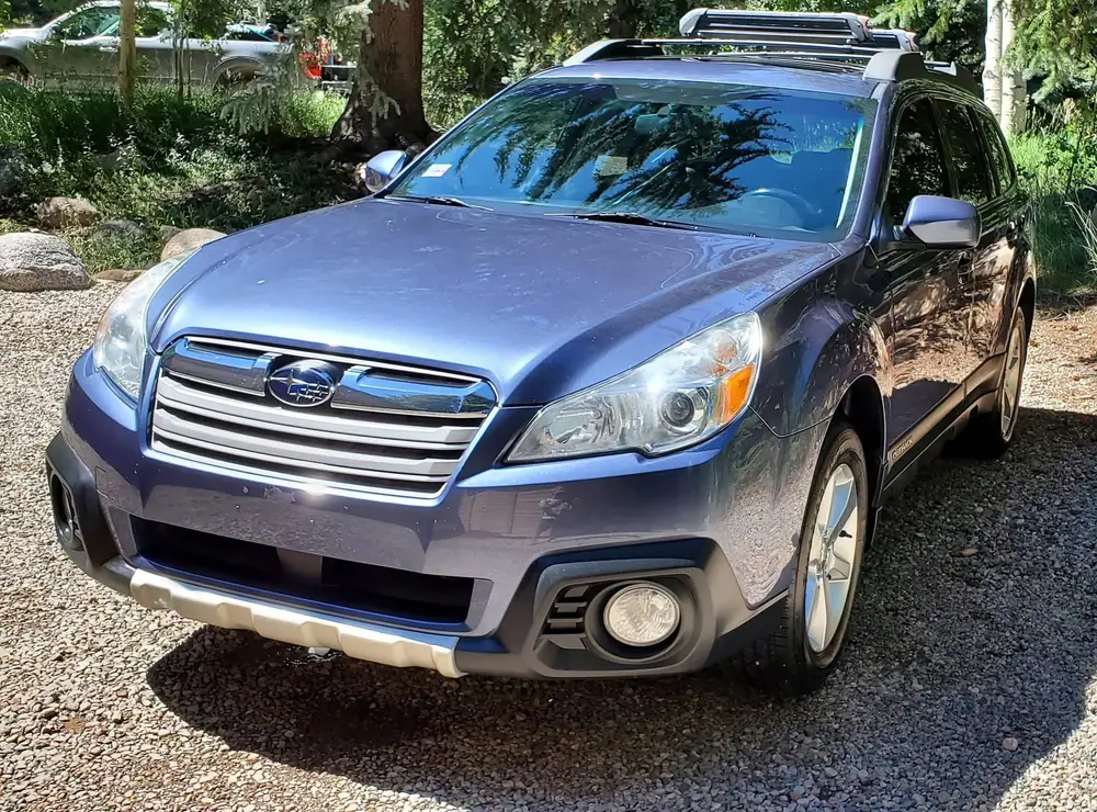 Blue Subaru Outback detailed in a driveway among the pines