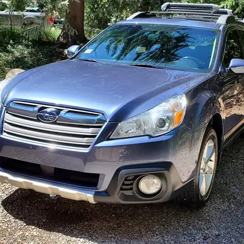 Blue Subaru Outback detailed in a driveway among the pines